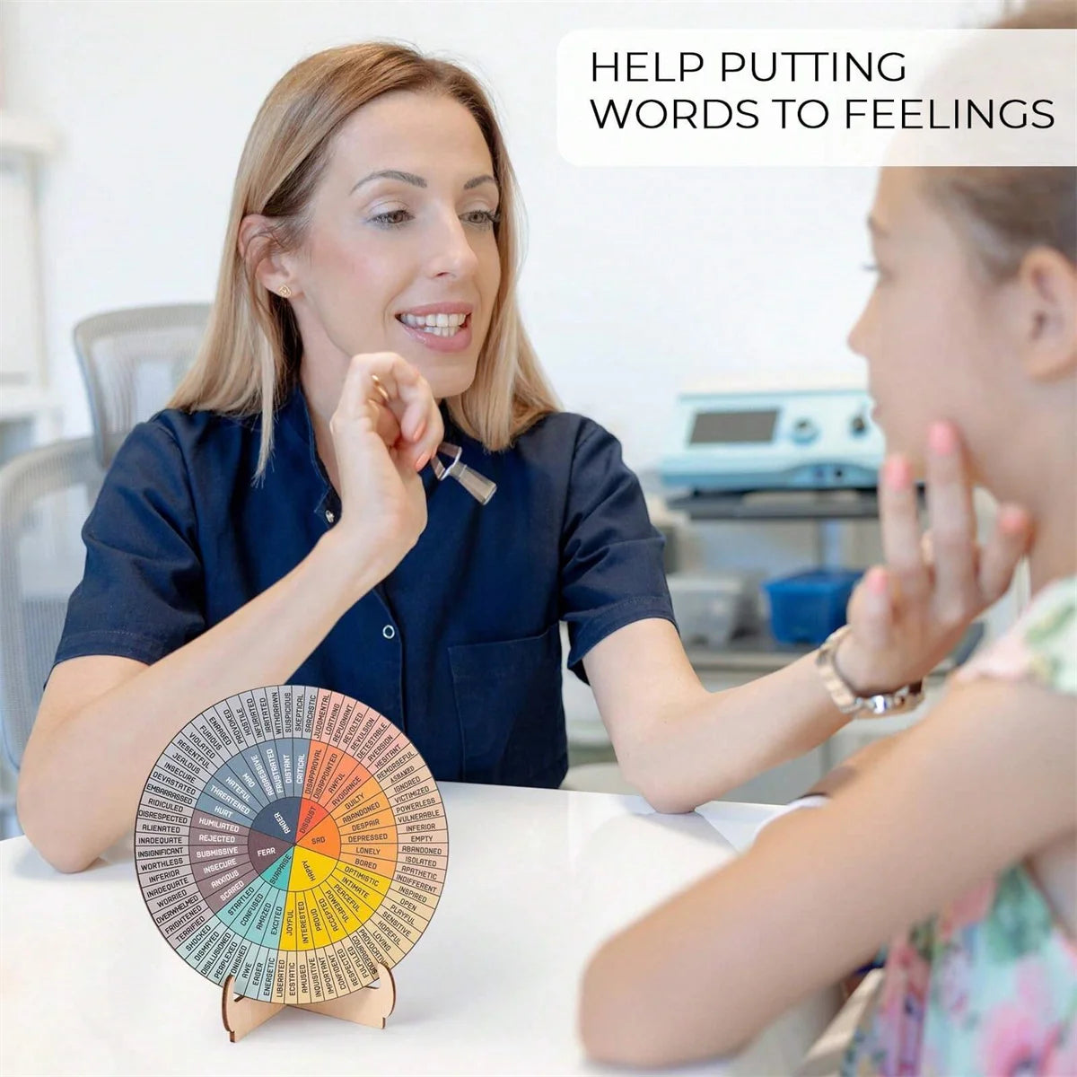 Feelings wheel chart used as mental health decor on a therapist’s desk beside notebooks and plants