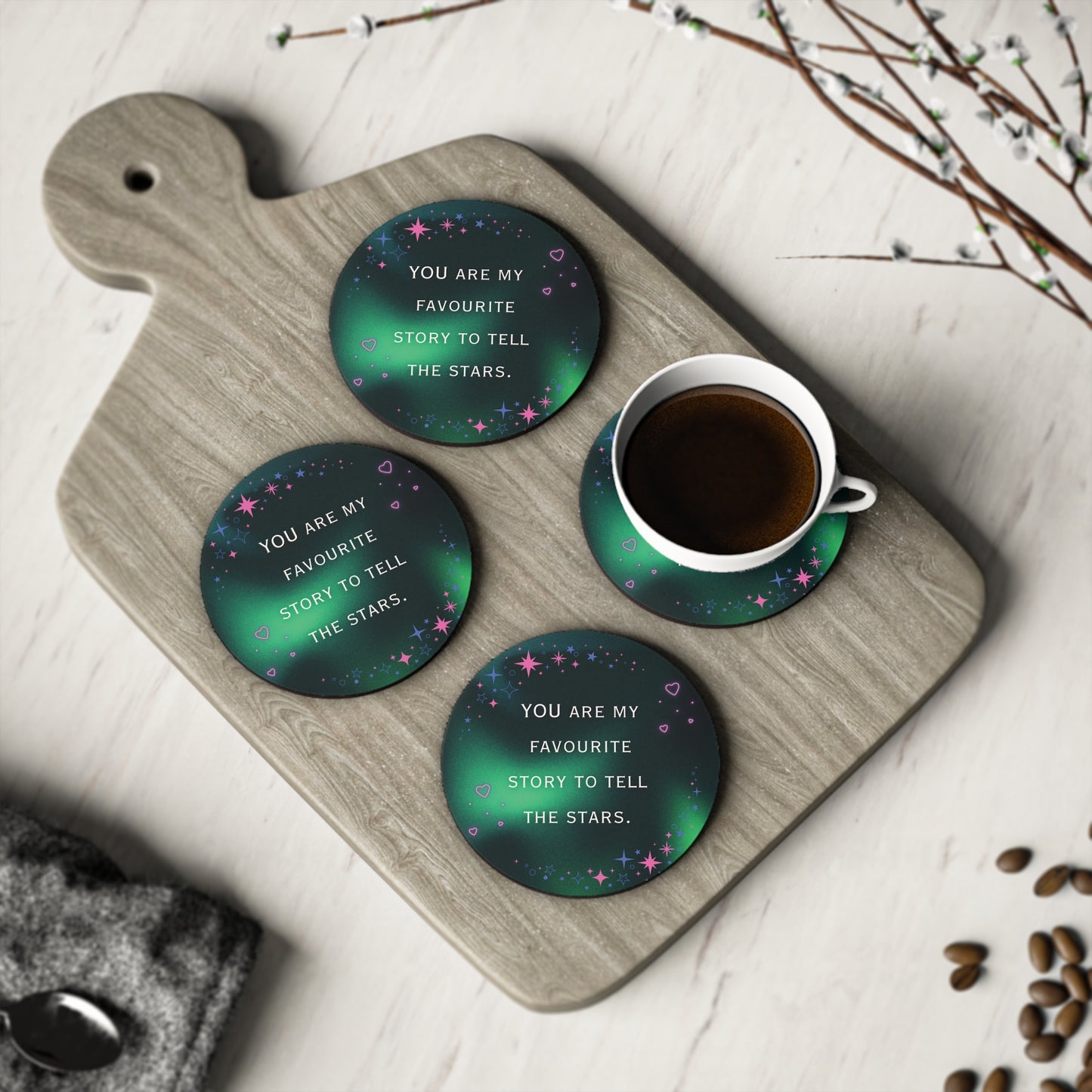 Green coasters with motivational text on a wooden cutting board with a cup of coffee.