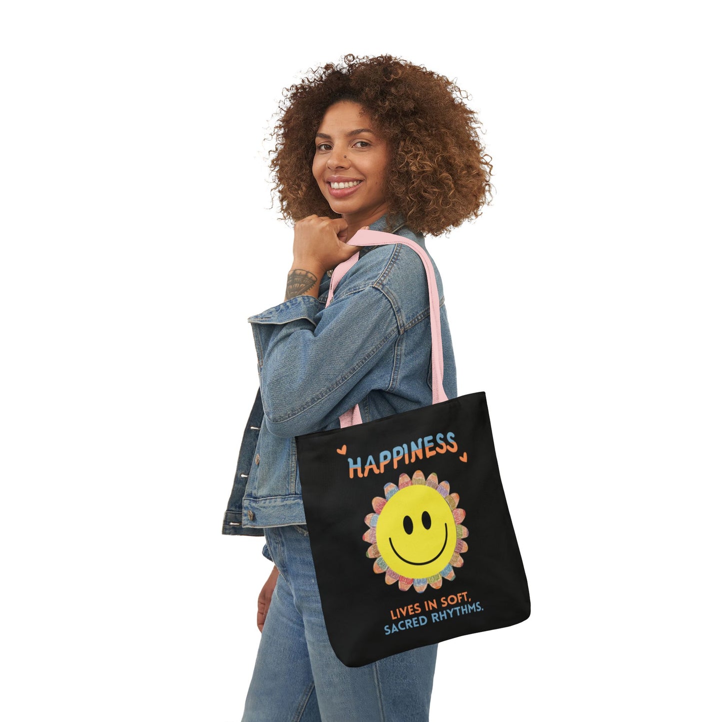 Woman holding a black tote bag with a smiley face and text design on a white background