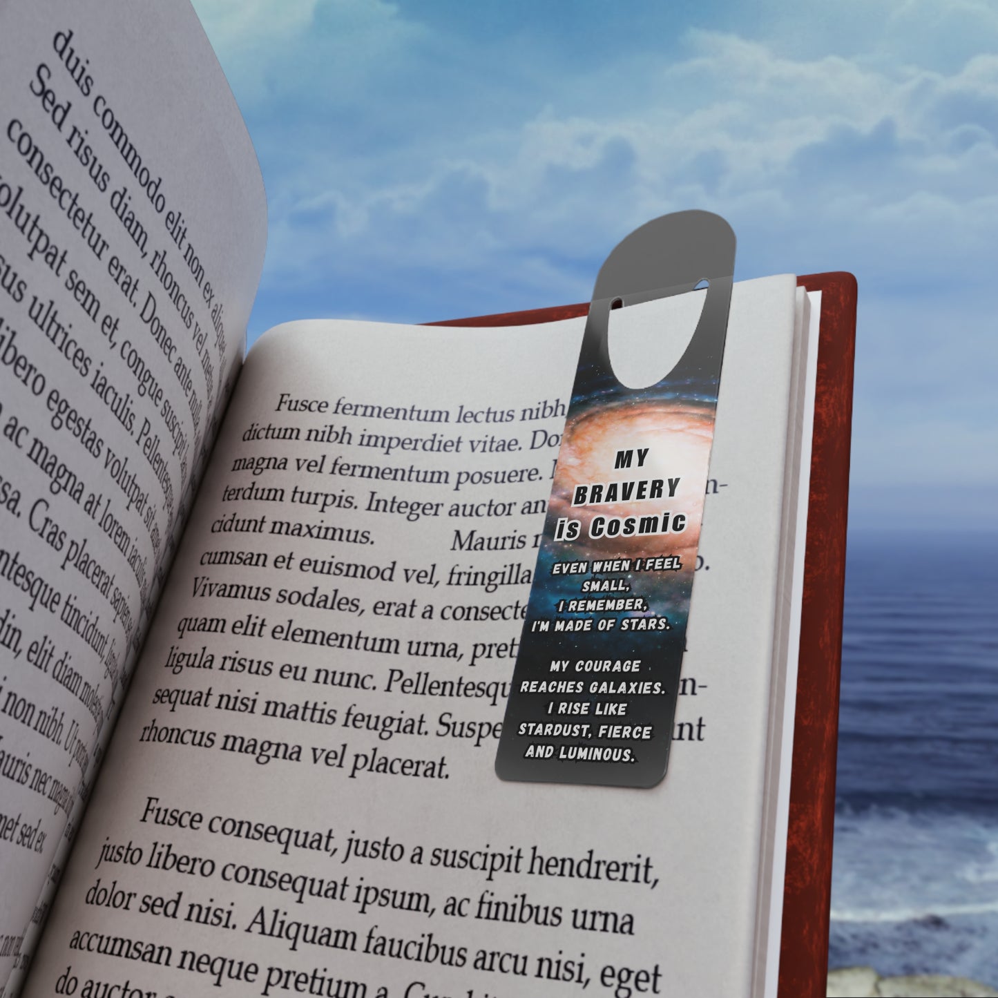 Open book with a bookmark featuring text, against a scenic background of water and sky.