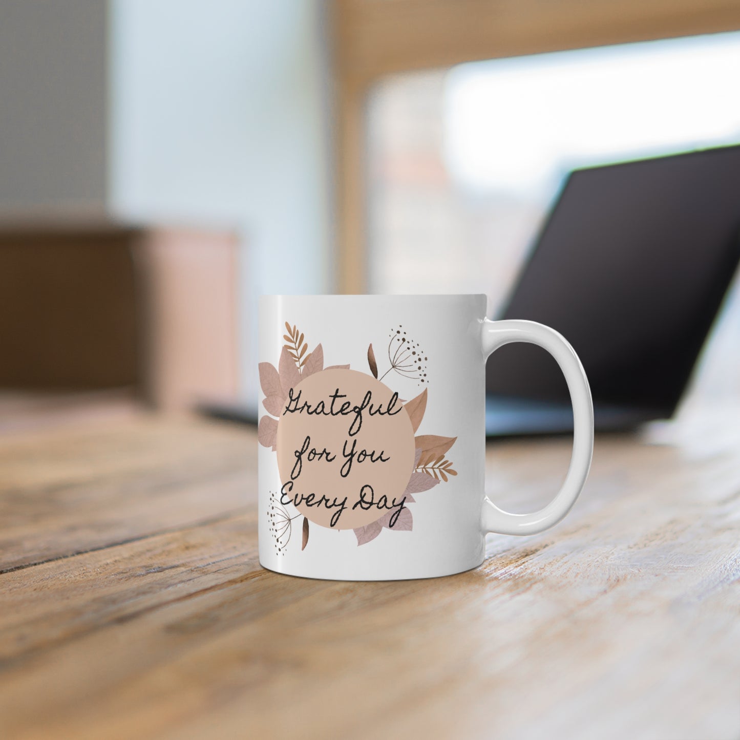 White mug with floral design and text on a wooden surface