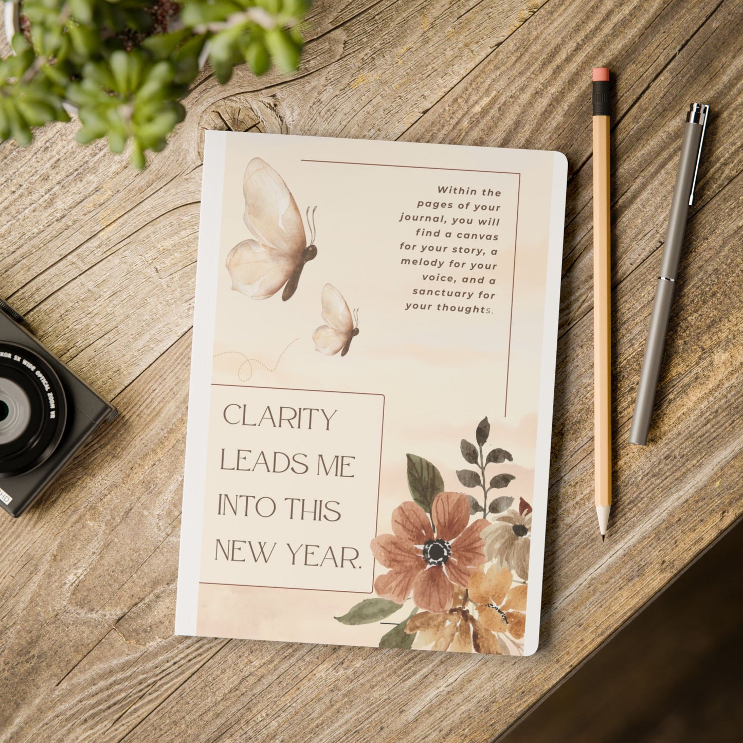 Notebook with floral design and text on a wooden surface with a pen and pencil.