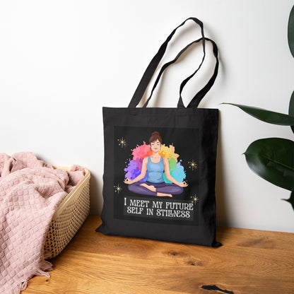 Black tote bag with a colorful design and text on a wooden surface.