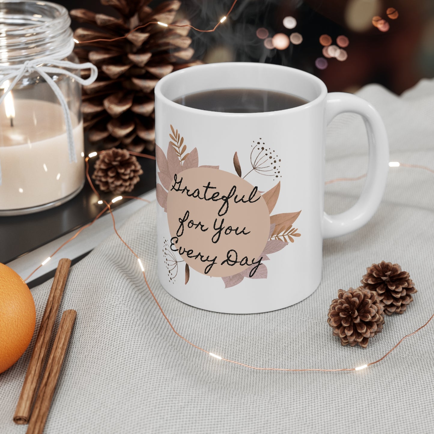 White mug with 'Grateful for You Every Day' text on a table with decorative items.