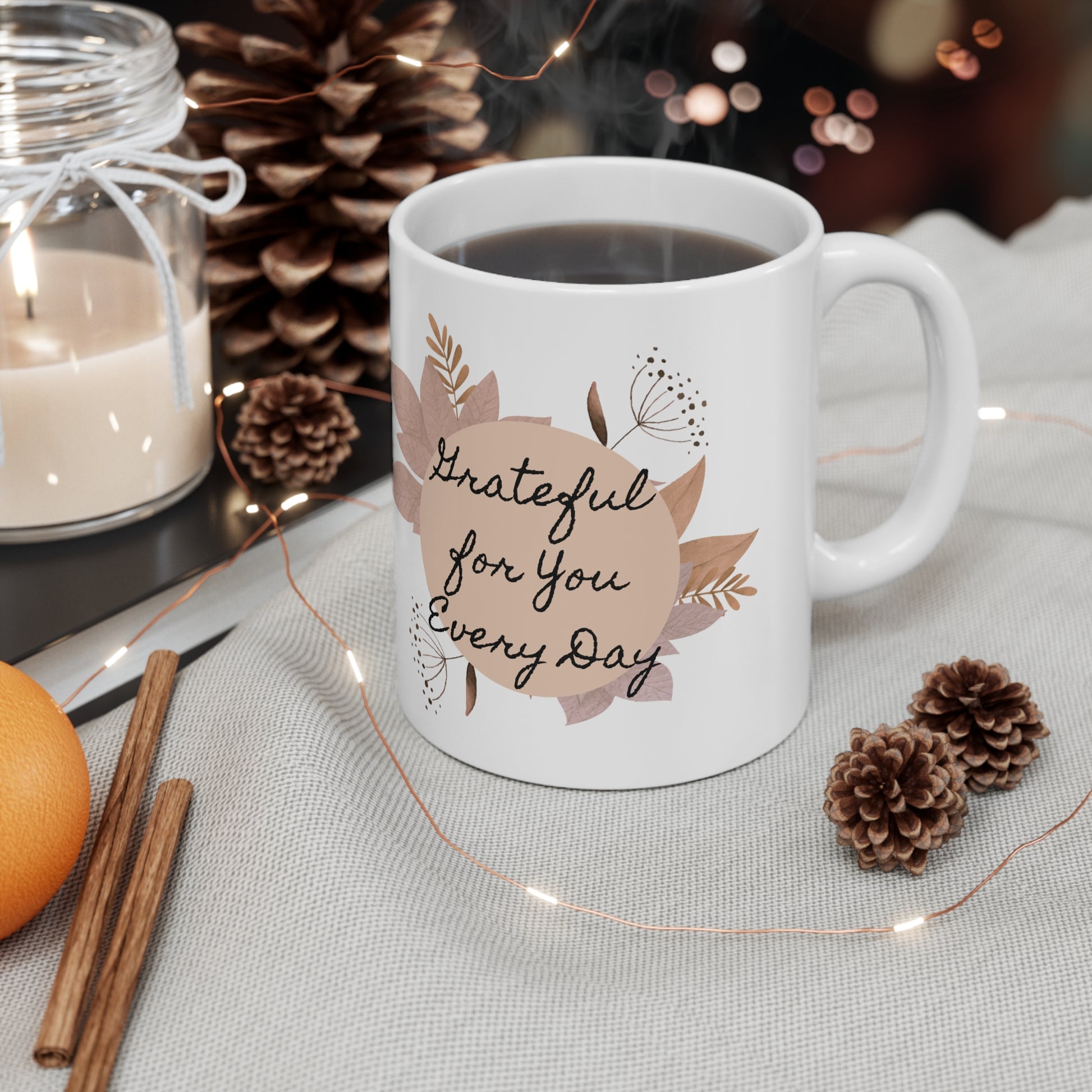 White mug with 'Grateful for You Every Day' text on a table with decorative items.