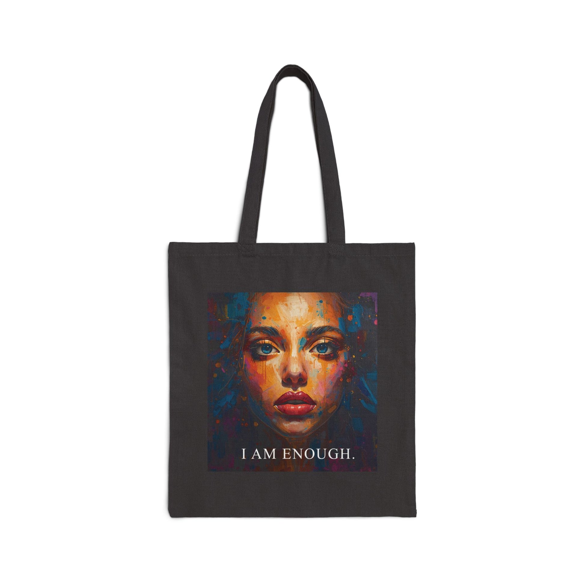 Black tote bag with a colorful face design and 'I AM ENOUGH' text on a white background