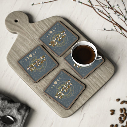 Set of four coasters with moon phases and 'Aligned by the Stars' text on a wooden tray with a cup of coffee.