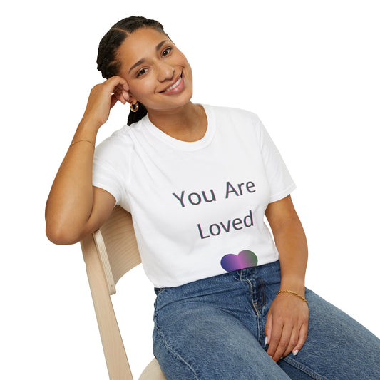 A lovely woman wearing a white t-shirt with 'You Are Loved' text sitting on a chair.