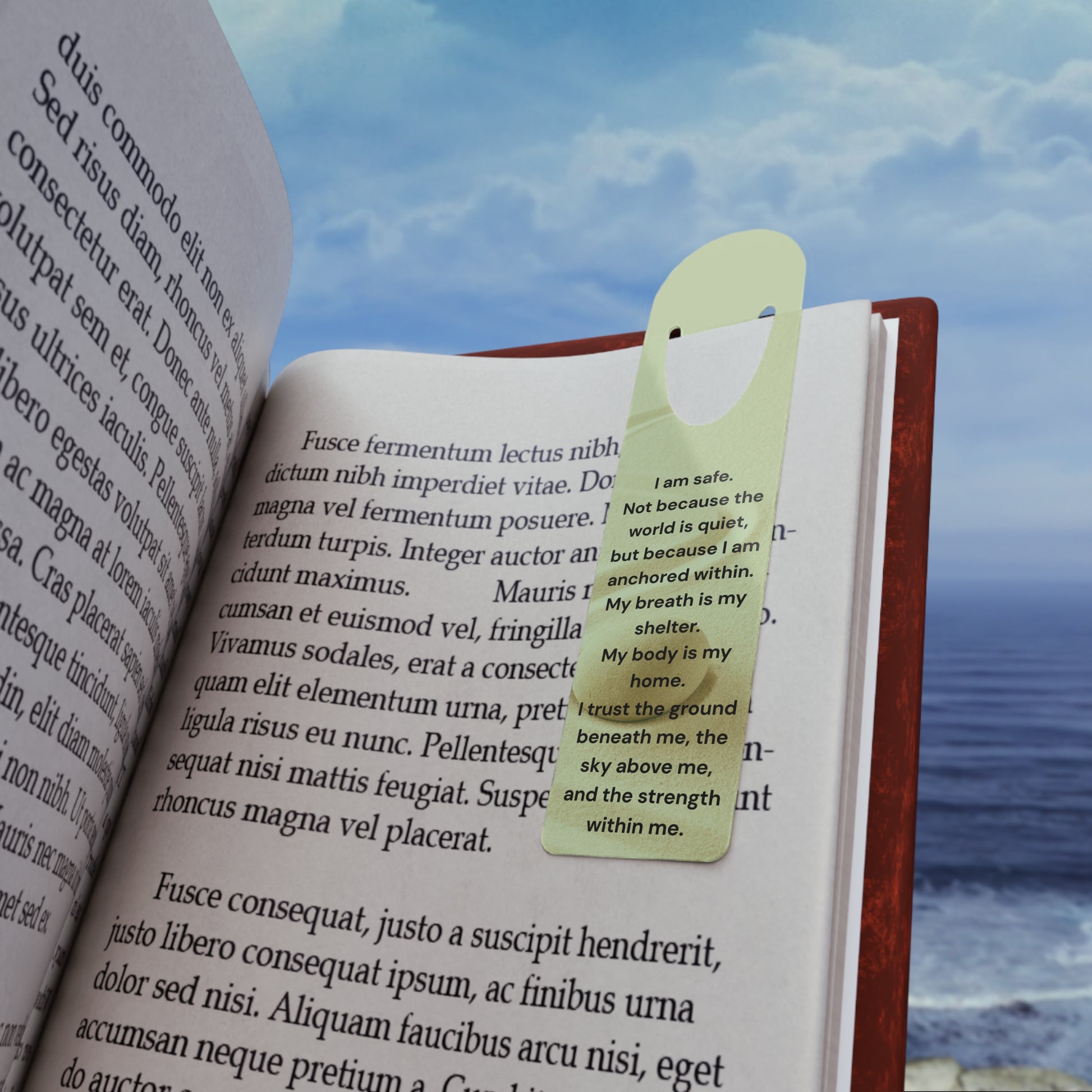 Open book with a green bookmark against a scenic background of water and sky.