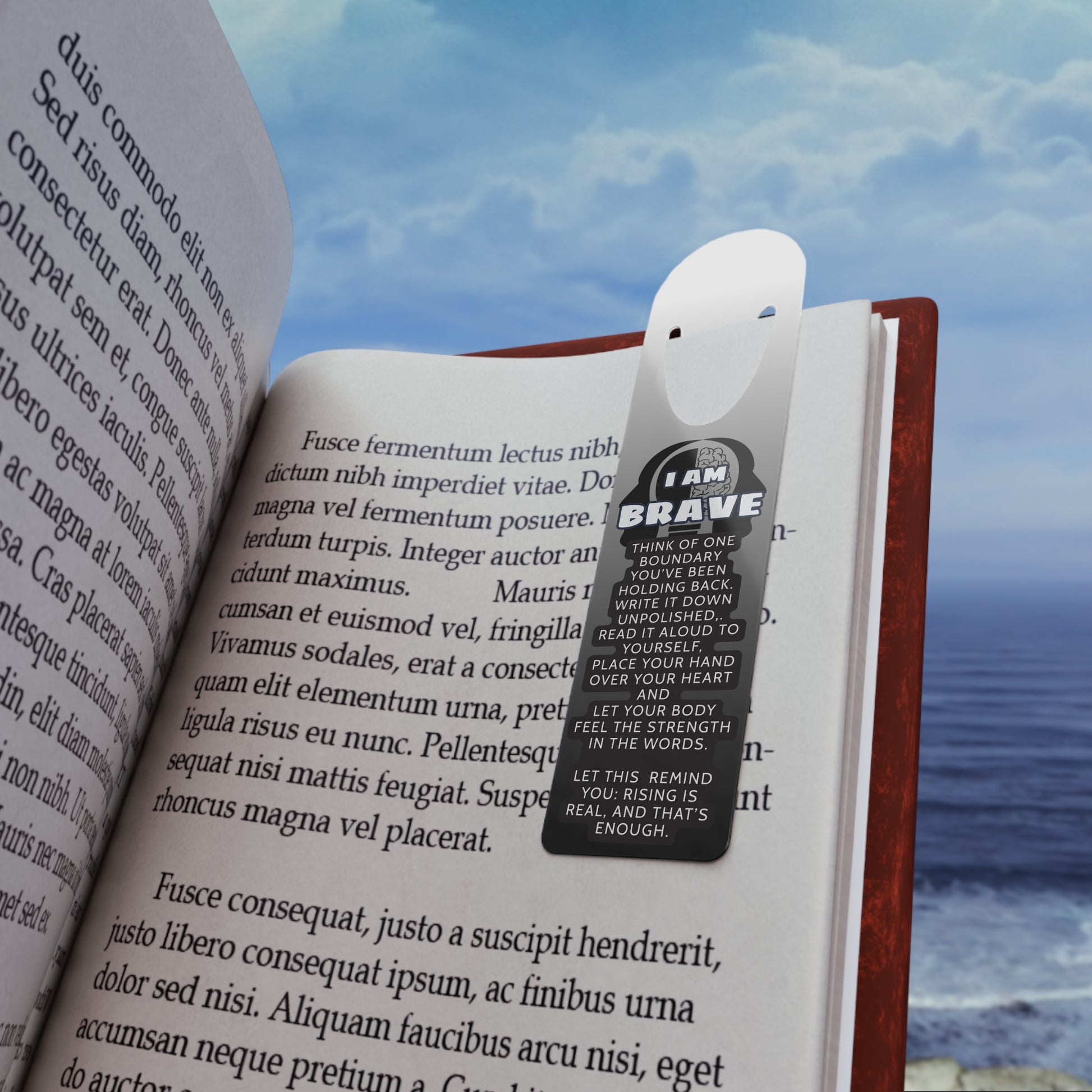 Open book with a bookmark featuring the text 'I AM BRAVE' against a scenic background.