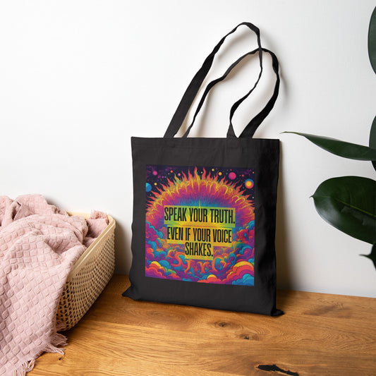 Black tote bag with colorful design and text on a wooden surface. Speak Your Truth Canvas Tote Bag Psychedelic Rainbow Daily Reminder Quote