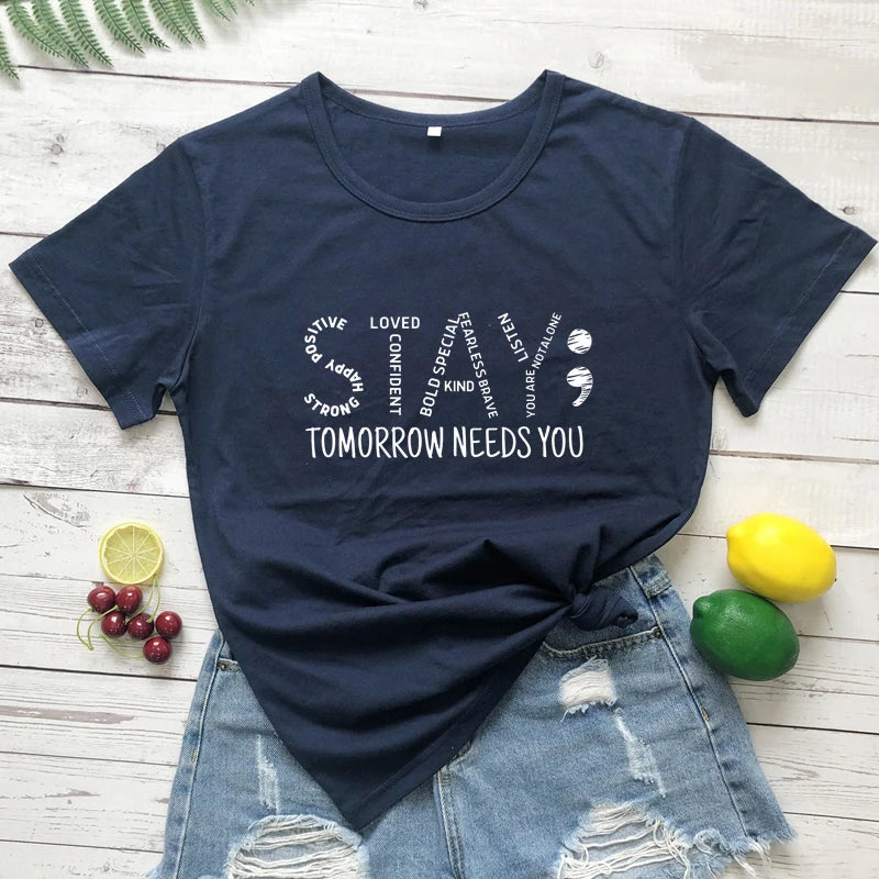 Navy blue t-shirt with motivational Stay Tomorrow Needs You Women’s Suicide Prevention Awareness T-Shirt | Mental Health Matters Teequote on a wooden surface with fruit 