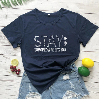 Navy blue t-shirt with motivational Stay Tomorrow Needs You Women’s Suicide Prevention Awareness T-Shirt | Mental Health Matters Teequote on a wooden surface with fruit 